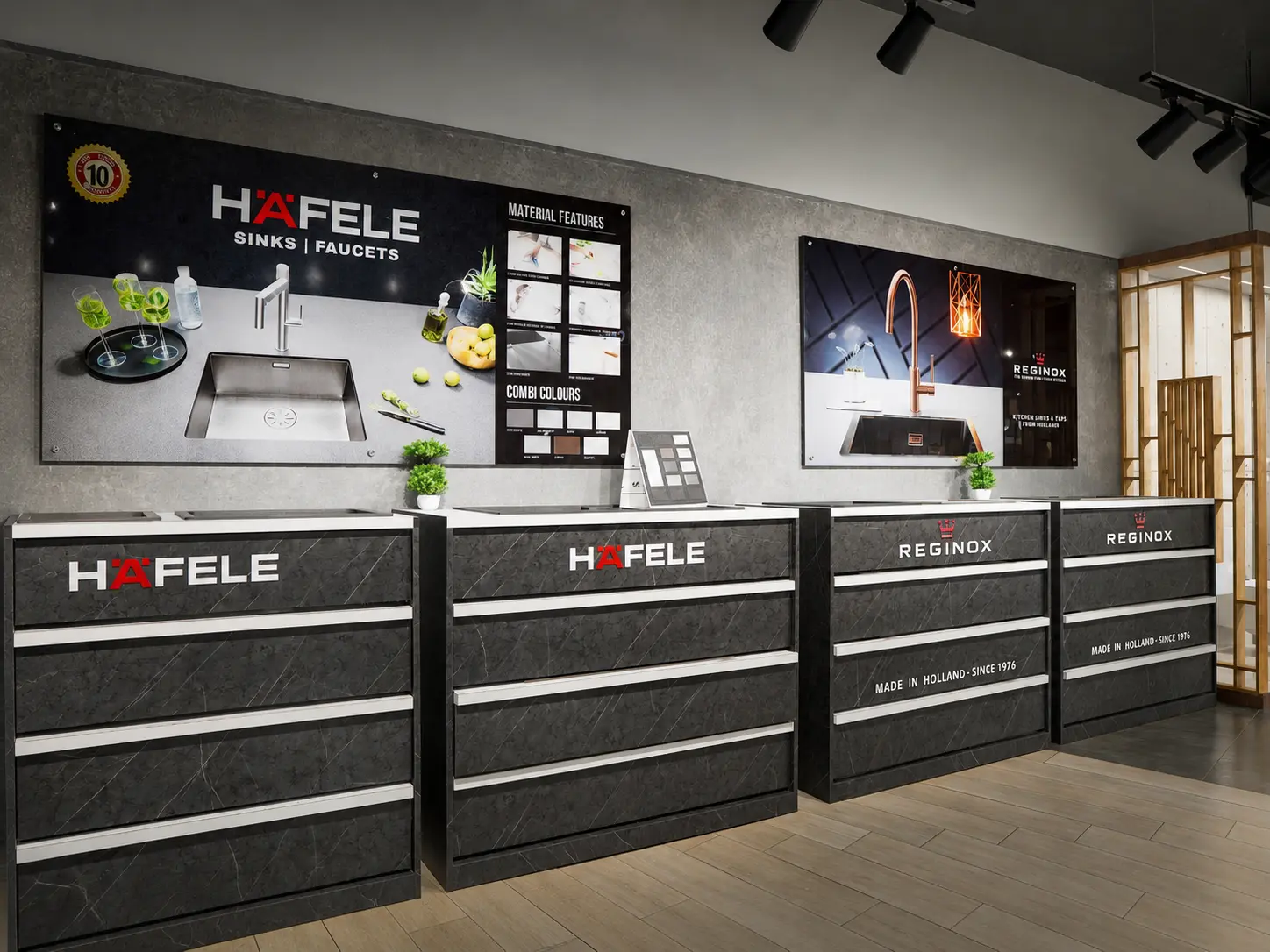 Kitchen sink and faucet display counters featuring Hafele and Reginox showroom branding.
