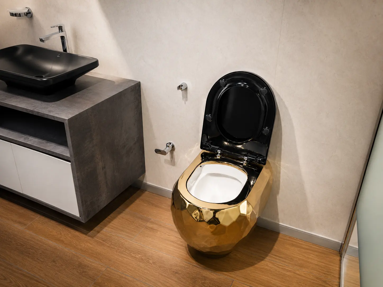 Luxury bathroom suite with a gold finish WC and black basin display.