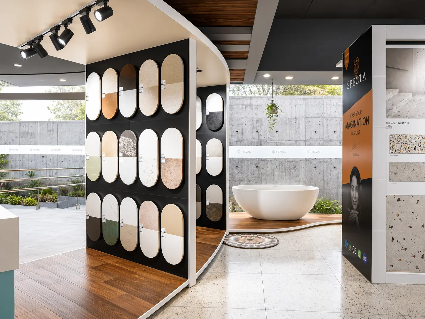 Surface sample wall beside a freestanding bathtub in a bright showroom zone.